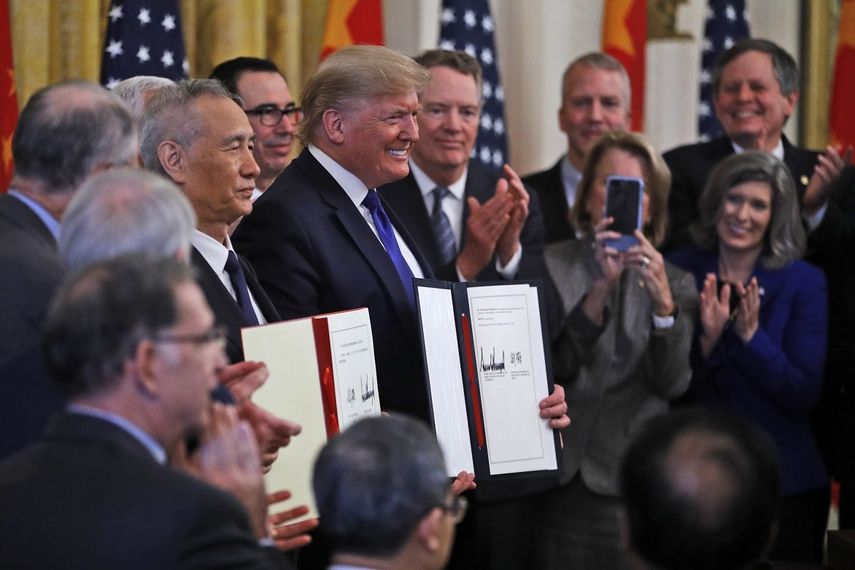 El presidente Donald Trump, centro, y el viceprimer ministro chino Liu He, izquierda, sostienen el acuerdo comercial después de haberlo firmado en la Sala Este de la Casa Blanca, el miércoles 15 de enero de 2020 en Washington.