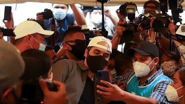 El presidente Nayib Bukele posa para una selfie con un trabajador electoral, mientras vota en las elecciones locales y legislativas en un colegio electoral en San Salvador, El Salvador, el domingo 28 de febrero de 2021.