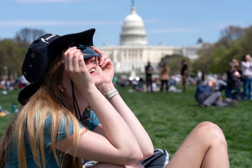 Las personas usan gafas protectoras mientras se reúnen para observar cómo la luna cubre parcialmente el sol durante un eclipse solar total, visto desde el National Mall en Washington, el lunes 8 de abril de 2024.&nbsp;