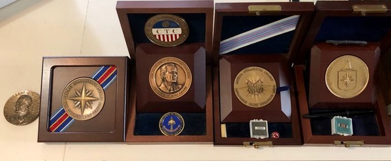 Condecoraciones de Ric Prado, entre las que se encuentran la Medalla a la excelencia en el antiterrorismo; la más alta condecoración a un oficial de la CIA (Medalla por la carrera distinguida de Inteligencia) y la recibida por más de 24 años de servicio en la CIA.         
