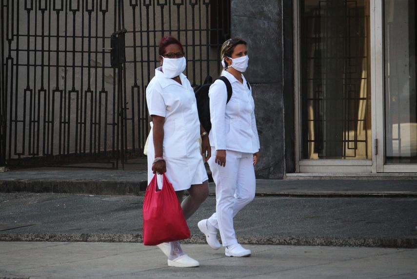 Dos enfermeras usas mascarillas faciales mientras caminan por una calle en La Habana, Cuba.