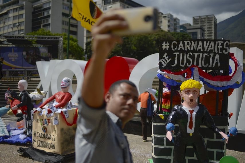 Un hombre se toma una selfie con figuras que representan al presidente Nicol&aacute;s Maduro, al jefe de la Asamblea Nacional Constituyente, Diosdado Cabello y al presidente estadounidense Donald Trump en Caracas, Venezuela, el martes 25 de febrero de 2019.