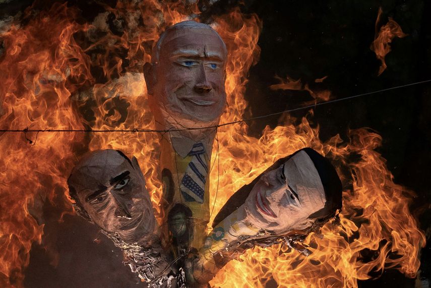 Cabezas de maniquíes que representan, de izquierda a derecha, a un político venezolano corrupto -como Maduro-, el presidente Joe Biden y la líder opositora María Corina Machado, están siendo quemados durante el tradicional ritual de Quema de Judas en el barrio San Agustín, en Caracas, el 9 de abril de 2023.
