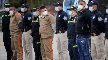Integrantes de la guerrilla del ELN Yamit Picon (L-2) y Henry Trigos (L-5), y Alexander Montoya Usuga (R-2), integrante de la banda narcotraficante Clan del Golfo, son escoltados por policías y agentes de la Interpol antes su extradición a Estados Unidos, en la Base Antinarcóticos de la Policía Nacional en Bogotá, el 19 de agosto de 2021.