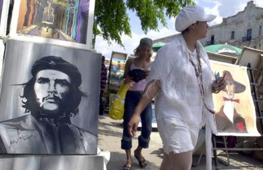 Una santera cubana pasa ante una pintura del Che Guevara en La Habana Vieja, donde artesanos cubanos ofrecen sus productos a los turistas extranjeros. (EFE)