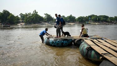 El migrante venezolano Gilberto Rodríguez (R) cruza el río Suchiate con su perro llamado Negro (Black) y sus compañeros migrantes Darwin Montiel (2-L) y Sergio Muñoz (C), en una balsa improvisada en Tecun Uman, Guatemala, en la frontera con Ciudad Hidalgo, México.