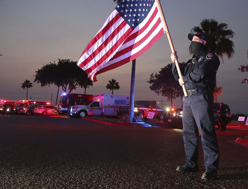 Homer Garza, bombero en Edinburg, ondea una bandera de Estados Unidos mientras los equipos de emergencias de la ciudad muestran su apoyo al personal m&eacute;dico y a sus pacientes, en el centro m&eacute;dico regional de Edinburg, el 22 de abril de 2020 en Edinburg, Texas.&nbsp;