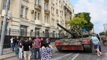 Soldados del grupo Wagner se sientan encima de un tanque en una calle de la ciudad de Rostov-on-Don, el 24 de junio de 2023, mientras pobladores de la localidad se acercan, lo que evidencia el control que tienen en la ciudad.