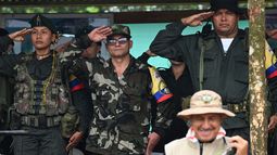 El máximo comandante de la disidencia de las FARC EP, alias Iván Mordisco (C), saluda a los militares junto al comandante Calarcá (R) durante una reunión con comunidades locales en San Vicente del Caguán, departamento de Caquetá, Colombia, el 16 de abril de 2023.