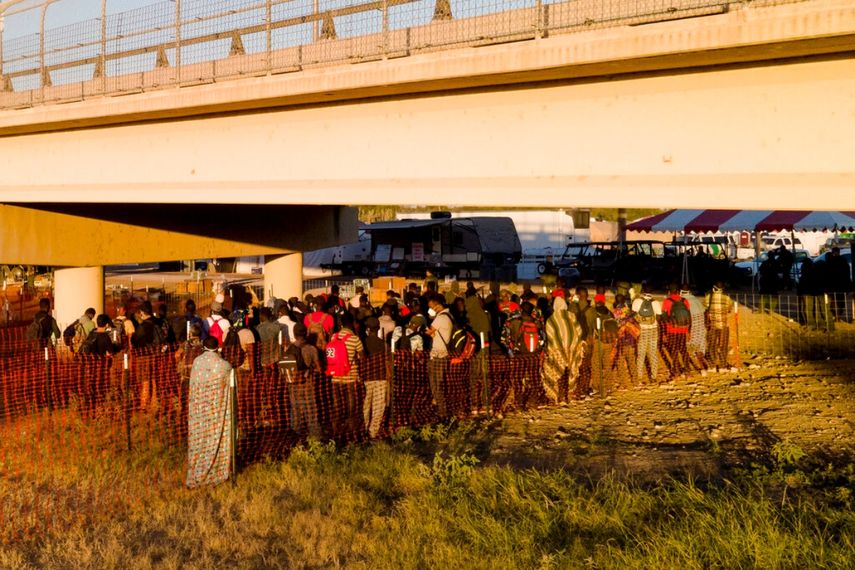 Migrantes, muchos procedentes de Haití, hacen fila el viernes 24 de septiembre de 2021 para subir a autobuses debajo del Puente Internacional de Del Rio, en Del Rio, Texas.