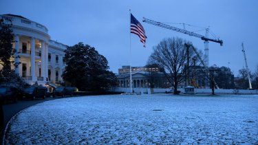 El edificio del Departamento del Tesoro de Estados Unidos (R) se ve detrás del sitio de construcción del nuevo salón de baile que reemplaza al Ala Este de la Casa Blanca en una noche nevada en Washington, DC.