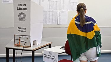 Una mujer envuelta en una bandera brasileña vota en un centro de votación durante las elecciones legislativas y presidenciales en Brasilia, Brasil, el 2 de octubre de 2022.&nbsp; &nbsp;