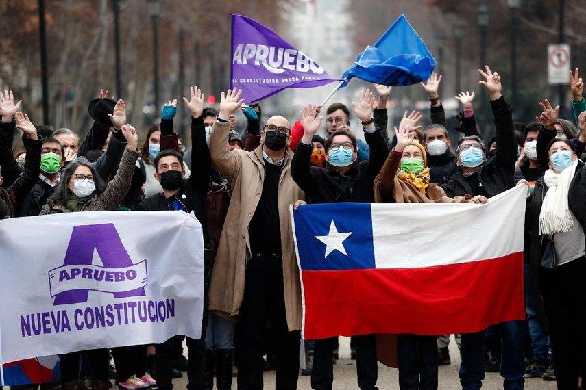 En esta foto de archivo tomada el 6 de julio de 2022, personas ondean mientras sostienen banderas de aprobación de la nueva Constitución y una bandera chilena en Santiago.