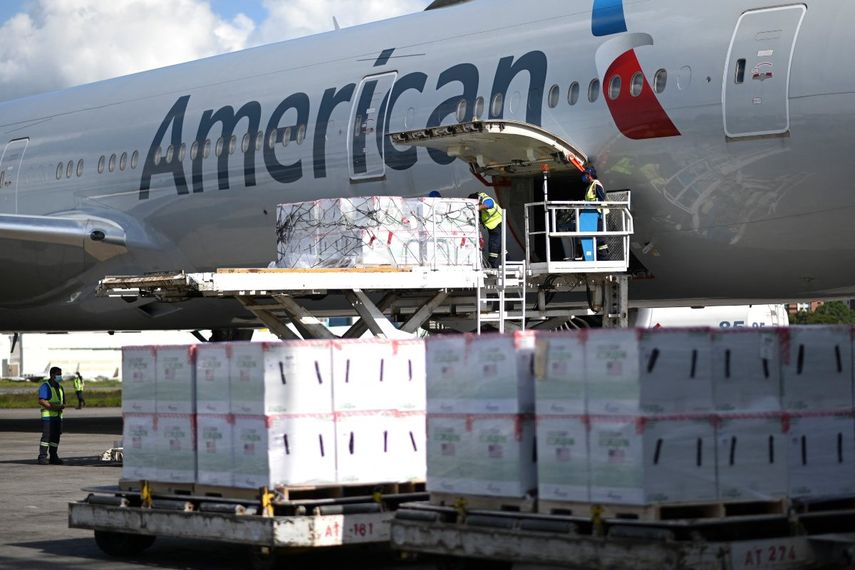 Los empleados del aeropuerto descargan un lote de tres millones de dosis de la vacuna Moderna contra COVID-19 donada por Estados Unidos desde un avión de American Airlines al aterrizar en el Aeropuerto Internacional Aurora en la Ciudad de Guatemala, el 20 de julio de 2021.