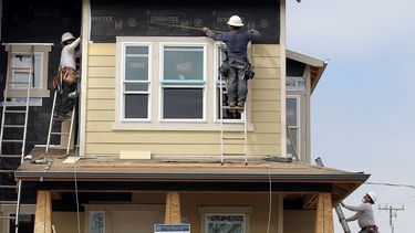 Empleados de una empresa de construcción de un dueño latino trabajan en una nueva propiedad.