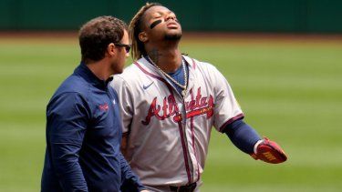 Ronald Acuña Jr., derecha, de los Bravos de Atlanta, camina para abandonar el campo acompañado del asistente médico después de sufrir una lesión al intentar robarse tercera durante la primera entrada del juego de béisbol en contra de los Piratas de Pittsburgh, el domingo 26 de mayo de 2024, en Pittsburgh.