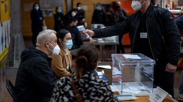 Un hombre que trabaja en un centro de votación colocado en un mercado pasa un control de temperatura corporal durante las elecciones regionales en Cataluña, en Barcelona, el domingo 14 de febrero de 2021.