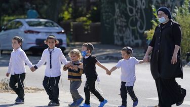 En esta fotograf&iacute;a de archivo del 28 de septiembre de 2020, una mujer con mascarilla por la pandemia de coronavirus y varios ni&ntilde;os cruzan una concurrida calle en el vecindario de Midwood, distrito de Brooklyn, en la Ciudad de Nueva York.