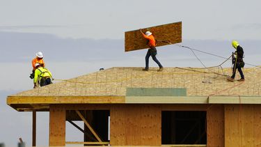 Empleados trabajan en la base del techo de una vivienda en construcción.