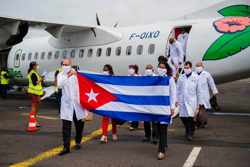 En esta foto de archivo tomada el 26 de junio de 2020, el médico jefe Abel Roberto Fuentes Santiesteban (izq.) Sostiene una bandera cubana cuando llega con una delegación de médicos cubanos al aeropuerto Martinica-Aime-Cesaire en Le Lamentin, cerca de Fort- de-France, en la isla caribeña francesa de Martinica, como parte de un programa de asistencia médica en medio de la pandemia de COVID-19 causada por el nuevo coronavirus.&nbsp; &nbsp;