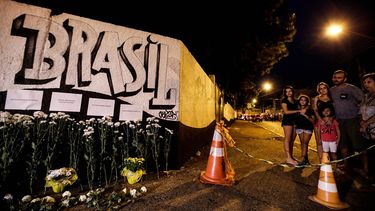 Fotografía de un grafiti con el nombre de la escuela Raúl Brasil en un muro adornado con ramos de flores y los nombres de las víctimas de una masacre este miércoles en Sao Paulo, Brasil.