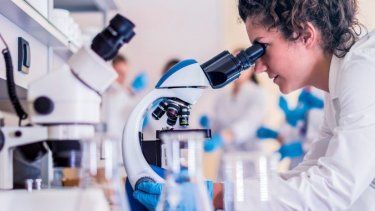 Una científica observa a través de un microscópio.&nbsp;