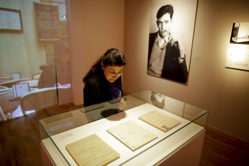 Una mujer mira páginas escritas a mano por el escritor Julio Cortázar, cerca de una fotografía del autor, en una exhibición que conmemora el centenario de su nacimiento en el Museo Nacional de Bellas Artes en Buenos Aires, Argentina, el martes 26 de agosto de 2014.