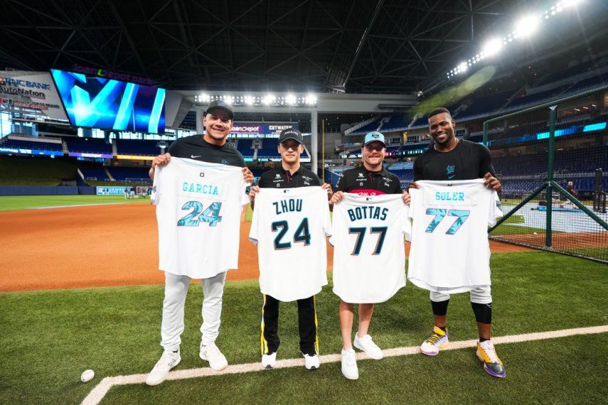 Los pilotos de Alfa Romeo, Valtteri Bottas y Zhou Guanyu posan con la camisa y jugadores de los Marlins de Miami, Avisail García y Jorge Soler en el LoanDepot Park