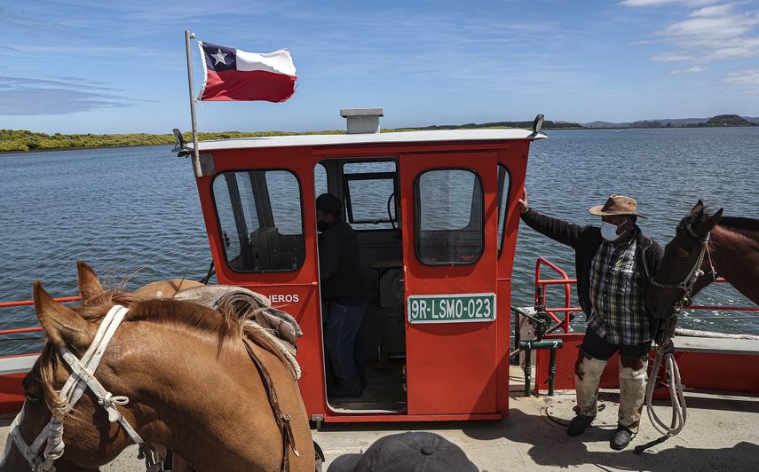 Un hombre mapuche cruza con sus caballos sobre el río Imperial en un ferry, un día antes de un eclipse solar total en Carahue, La Araucanía, Chile el domingo 13 de diciembre de 2020. El eclipse total será visible desde Chile y la región norte de la Patagonia de Argentina y como eclipse solar parcial en Bolivia, Brasil, Ecuador, Paraguay, Perú y Uruguay.&nbsp;