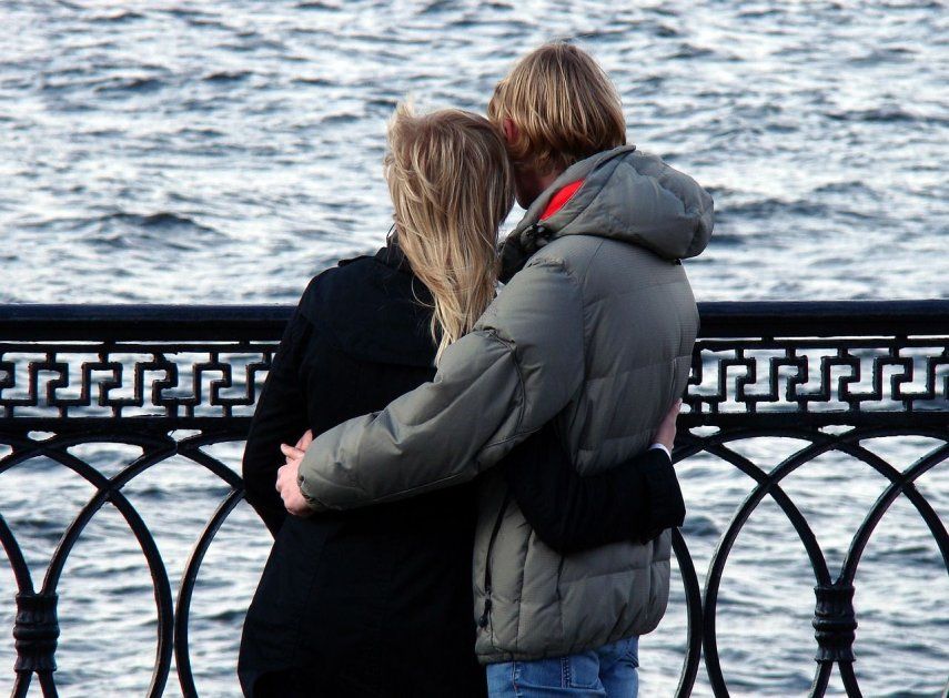 Una pareja de novios abrazados disfruta del paisaje del mar.