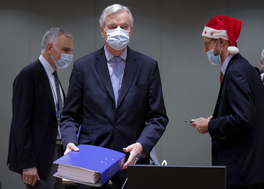 El negociador en jefe de la UE Michel Barnier (al centro) lleva una carpeta del acuerdo comercial posterior al Brexit en el edificio del Concejo Europeo en Bruselas.&nbsp;