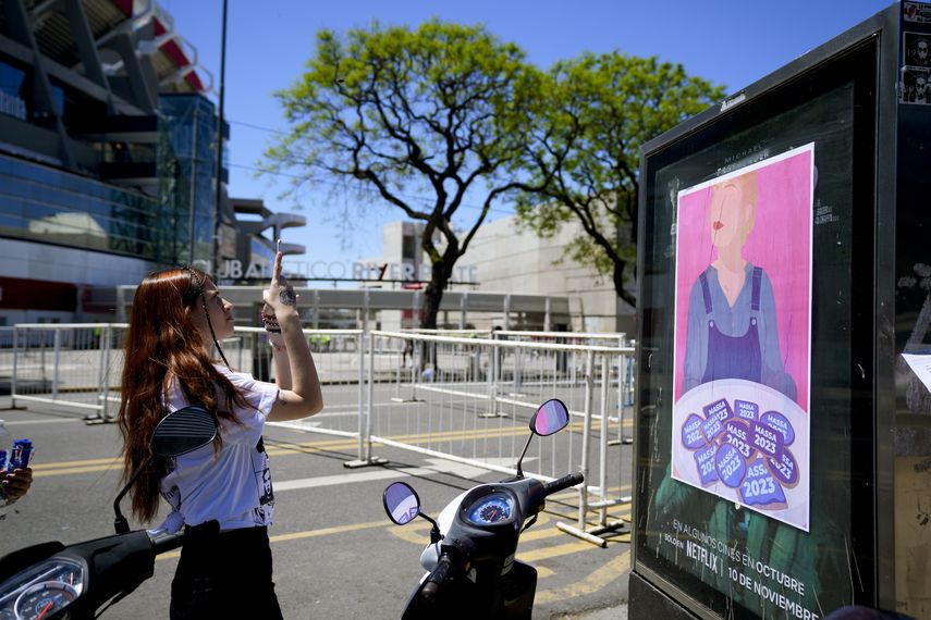 Una fanática de Taylor Swift toma una fotografía de un cartel que muestra un retrato inspirado en la cantante que tiene unas galletas con la frase Massa 2023, en el Estadio Monumental, antes de que se abran las puertas para el concierto de Swift en Buenos Aires, el jueves 9 de noviembre de 2023.