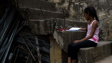 Una niña lee sentada en una escalera en una barriada de Petare, en Caracas, Venezuela.