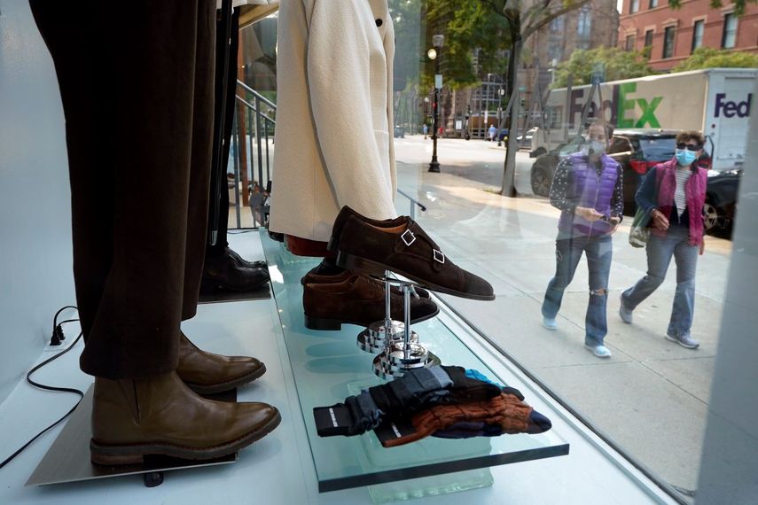 Dos personas pasan frente a una vidriera de una tienda minorista.