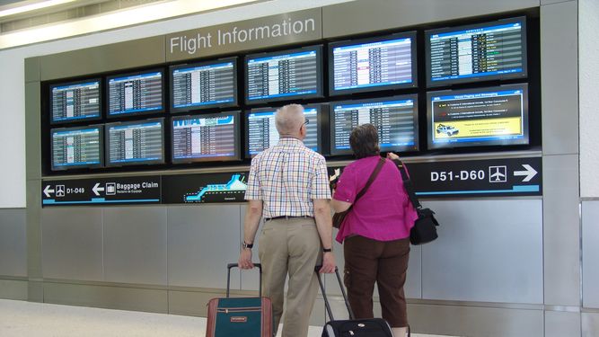 Dos pasajeros verifican hora de salida de su vuelo en el Aeropuerto Internacional de Miami.