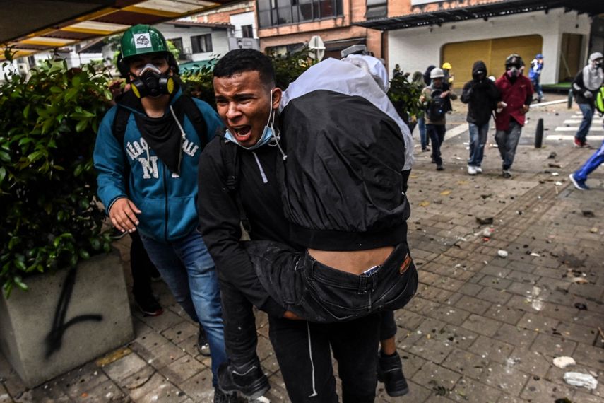 Un hombre lleva a un manifestante herido durante los enfrentamientos con la policía antidisturbios durante una protesta contra el gobierno en Medellín, Colombia, el 28 de mayo de 2021. Tres personas murieron el 28 de mayo durante las protestas contra el gobierno en la ciudad colombiana de Cali, dijeron las autoridades. el país marcó un mes completo de malestar social que se ha cobrado decenas de vidas.