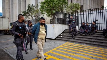 David Coronado Pérez, quien supuestamente es parte de una red de trata de personas, es escoltado por un oficial al final de su audiencia en la corte, en Ciudad de Guatemala, el viernes 4 de febrero de 2022.