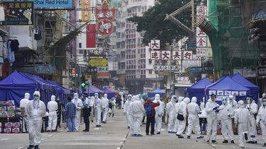 Investigadores gubernamentales con trajes para protegerse del coronavirus se reúnen el sábado 23 de enero de 2021 en el área de Yau Ma Tei, en Hong Kong. 