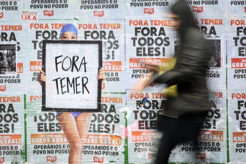 Una persona pasa frente a un muro lleno de carteles en contra del presidente de Brasil, Michel Temer, luego de que una nueva confesión sobre el pantano de corrupción en que parece haberse sumergido Brasil agravó la ya delicada situación del presidente y alcanzó además a sus antecesores Dilma Rousseff y Luiz Inácio&nbsp;Lula&nbsp;da&nbsp;Silva.