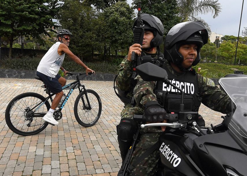 Un hombre pasa en bicicleta junto a soldados colombianos en motocicleta que patrullan en vísperas de las elecciones presidenciales en Medellín, Colombia, el 28 de mayo de 2026.