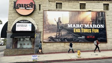 Los peatones pasan junto al club de comedia cerrado Laugh Factory, el lunes 16 de marzo de 2020, en Los Ángeles. El alcalde de Los Ángeles, Eric Garcetti, ordenó el domingo el cierre de todos los bares, clubes nocturnos, restaurantes, gimnasios y lugares de entretenimiento de la ciudad para evitar la propagación del coronavirus. 