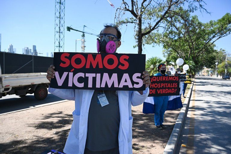 Un médico hondureño sostiene un cartel que dice 