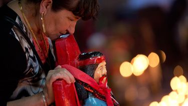 En esta imagen del 8 de noviembre de 2014, una mujer se apoya en una estatua del santo popular Gauchito Gil en un santuario construido en su honor por la gente que le atribuye milagros, en el aniversario de su muerte ein Alejandro Korn, Argenti