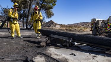 Bomberos de California examinan un poste de bajo voltaje calcinado en un incendio, el 25 de octubre de 2019, en Santa Clarita, California. 