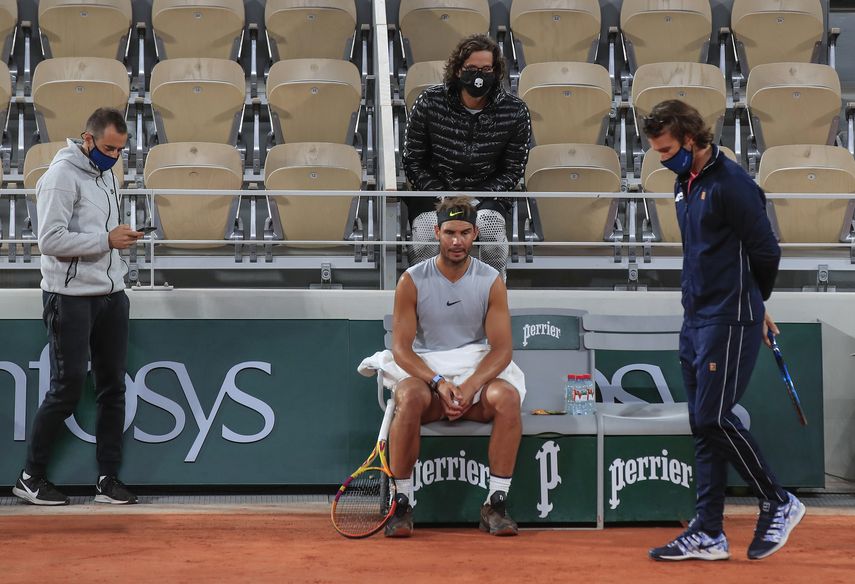 El espa&ntilde;ol Rafael Nadal, centro, su entrenador Francisco Roig, derecha, y parte de su equipo con cubrebocas se re&uacute;ne durante una pausa en una pr&aacute;ctica en el estadio Roland Garros en Par&iacute;s, el viernes 25 de septiembre de 2020