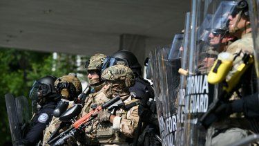 Oficiales de policía están flanqueados por miembros de la Guardia Nacional de California fuera del Edificio Federal durante una protesta en respuesta a las operaciones federales de inmigración en Los Ángeles, el 9 de junio de 2025.