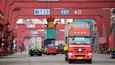 Varios camiones transportan contenedores en el puerto en Qingdao, China.