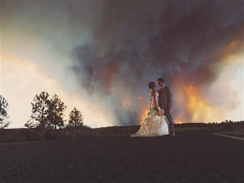 Los novios Michael Wolber y April Hartley posan para un retrato cerca de Bend, Oregon, con un incendio forestall como fondo el día de su boda (Foto AP)