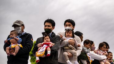 Los niños sostenidos por sus padres se paran antes de su partido en el festival de Japón Baby-cry Sumo, que se reanudó por primera vez en cuatro años debido a la pandemia de coronavirus, en el templo Sensoji en Tokio, el 22 de abril de 2023.