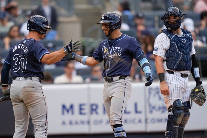 El panameño de los Rays de Tampa Bay, José Caballero (centro), celebra su cuadrangular con Ben Rortvedt (izquierda) ante la mirada del receptor de los Yanquis de Nueva York, Austin Wells (derecha), durante el noveno episodio del juego de béisbol en el Yankee Stadium, el 21 de julio de 2024, en Nueva York.